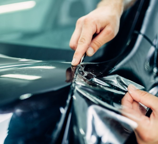 Worker hands installs car paint protection film